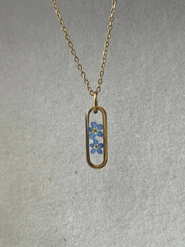 Collier médaillon ovale fond transparent myosotis, doré